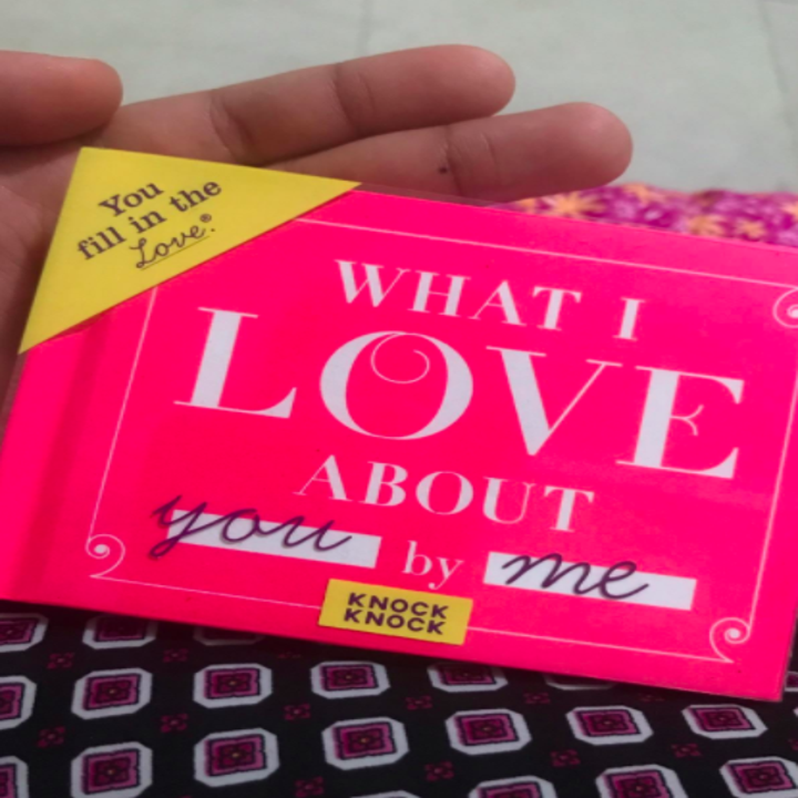 Reviewer holds bright pink book that says "What I Love About You by Me"