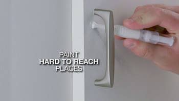 A person painting a part of their wall white with the touch-up paint pen