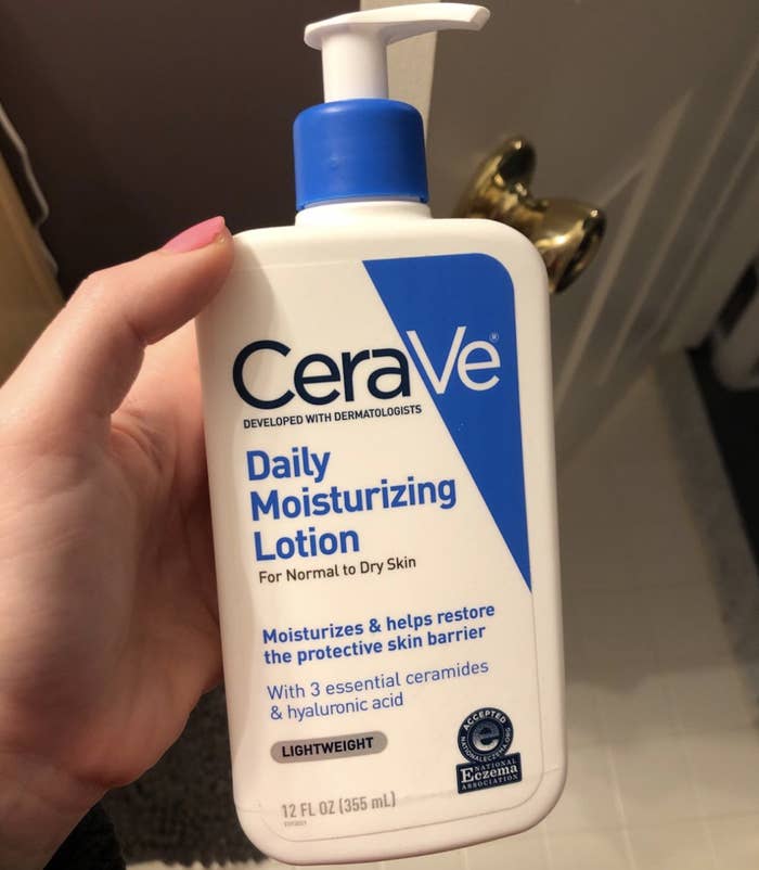 reviewer holding white and blue lotion bottle