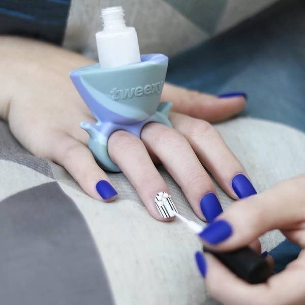 A person wearing the nail polish holder while painting their nails