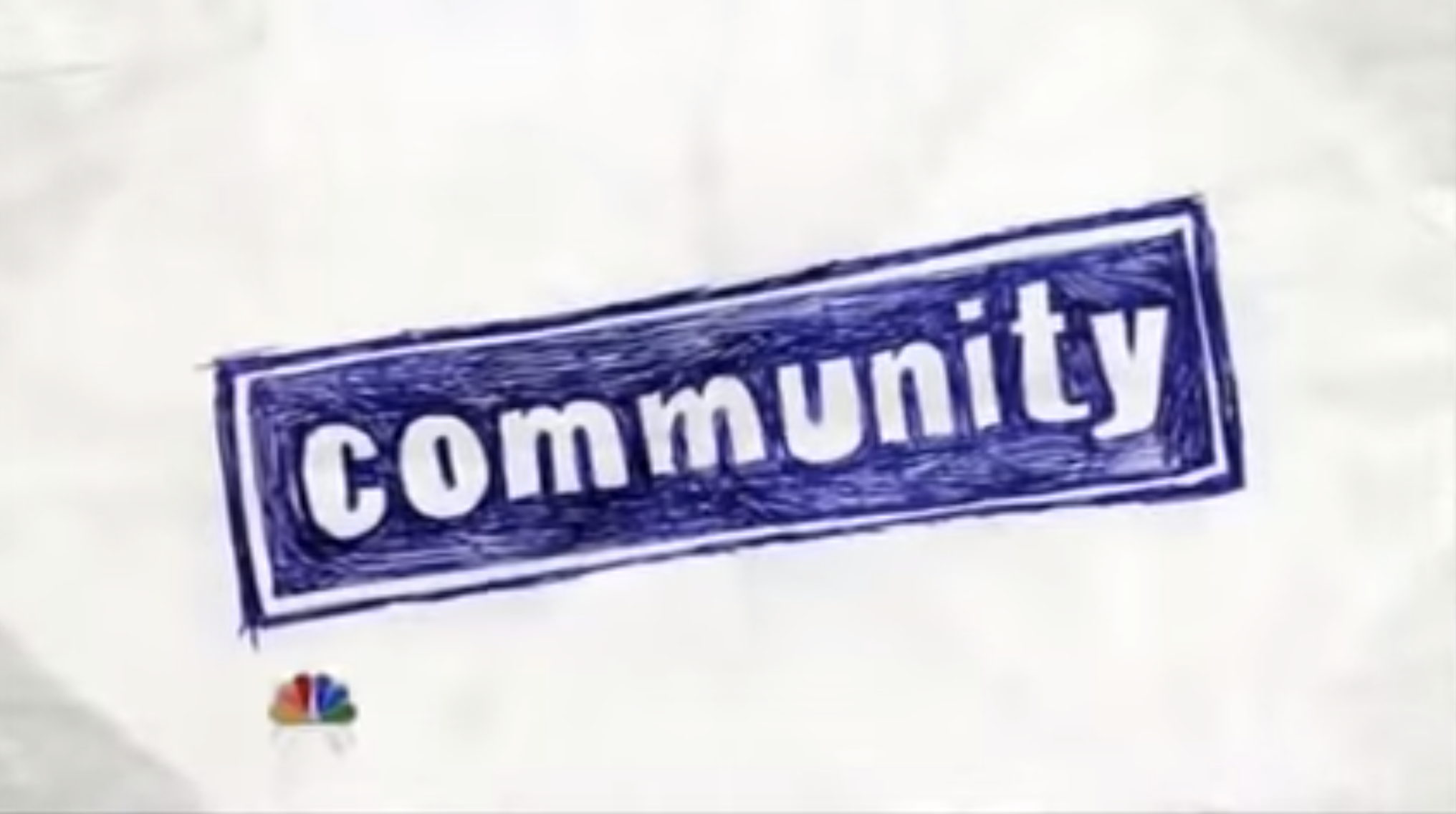 &quot;Community&quot; title card — which is the title of the show in blue ink on a white sheet of paper. 