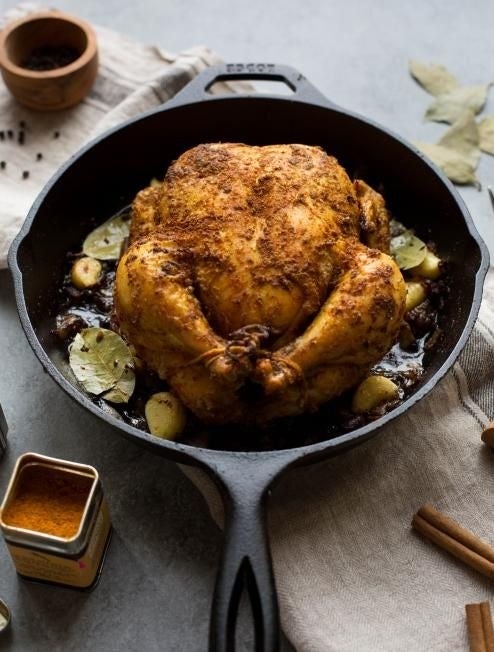 a cast-iron skillet with a whole roasted chicken in it