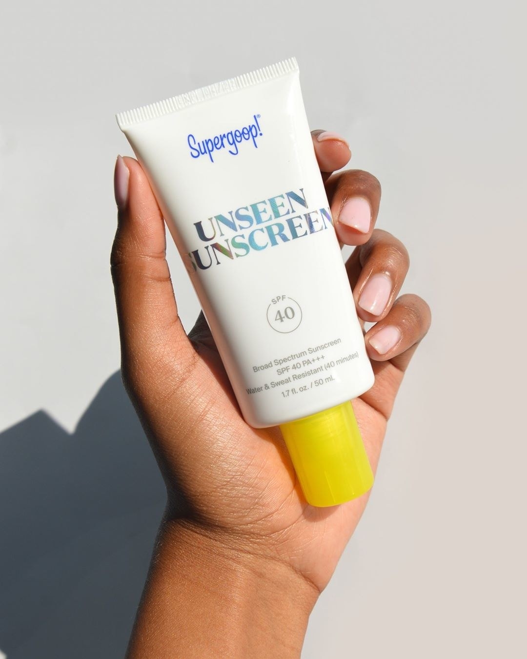 model holding white bottle of sunscreen with yellow cap