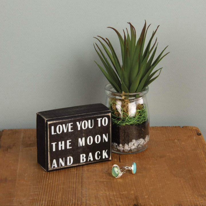 Black block sign that says "love you to the moon and back" on the front