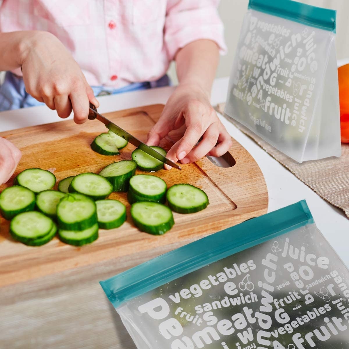 A person chopping up cucumbers and putting them in the bags