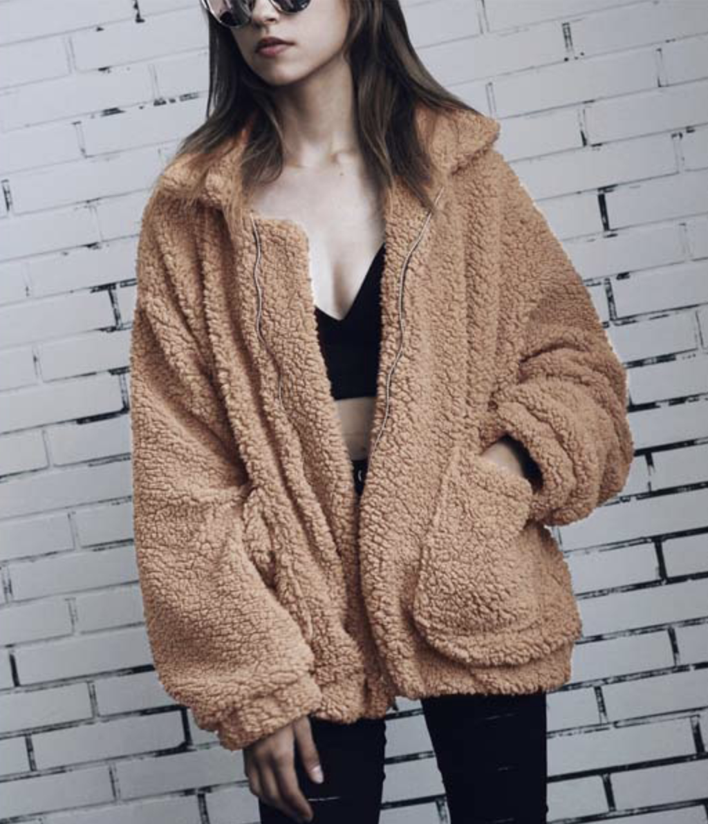 Model in a zippered camel colored faux shearling jacket 