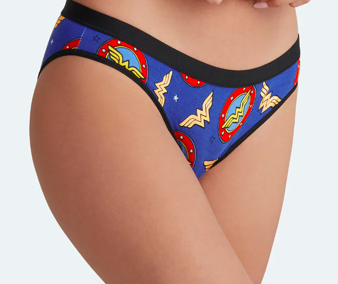 A model wearing the blue underwear printed with Wonder Woman logos with a black band and piping