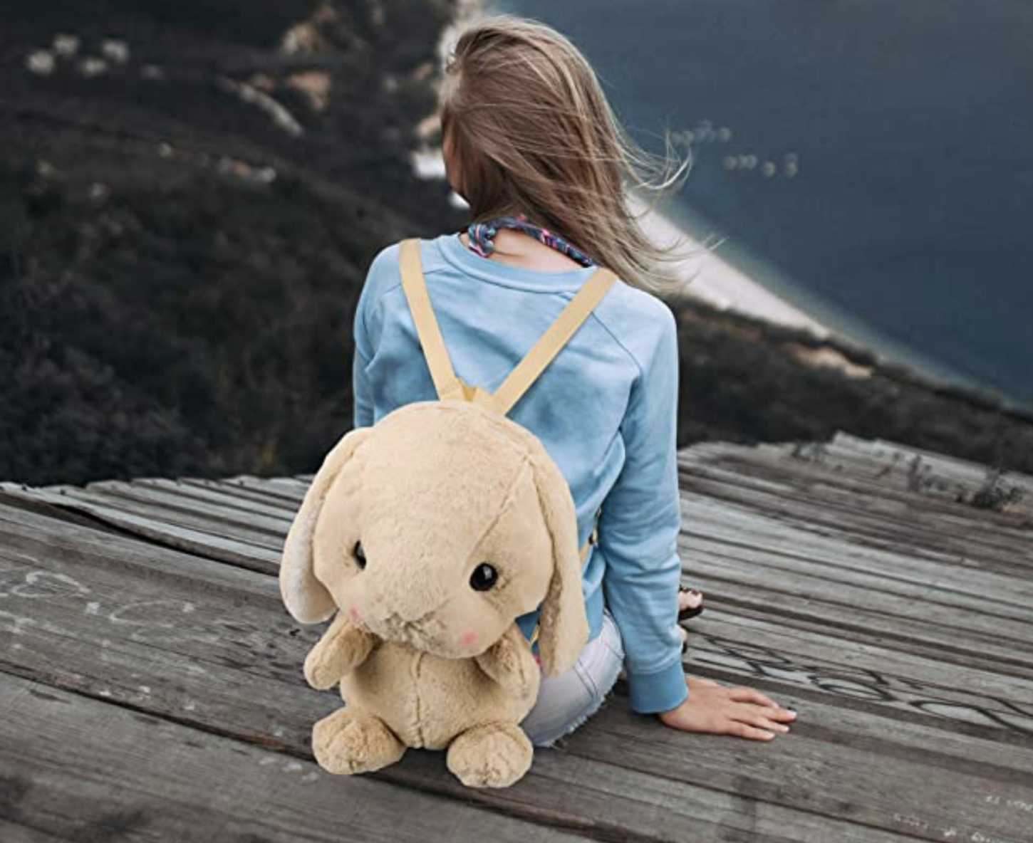 model wearing a beige plush bunny shaped backpack