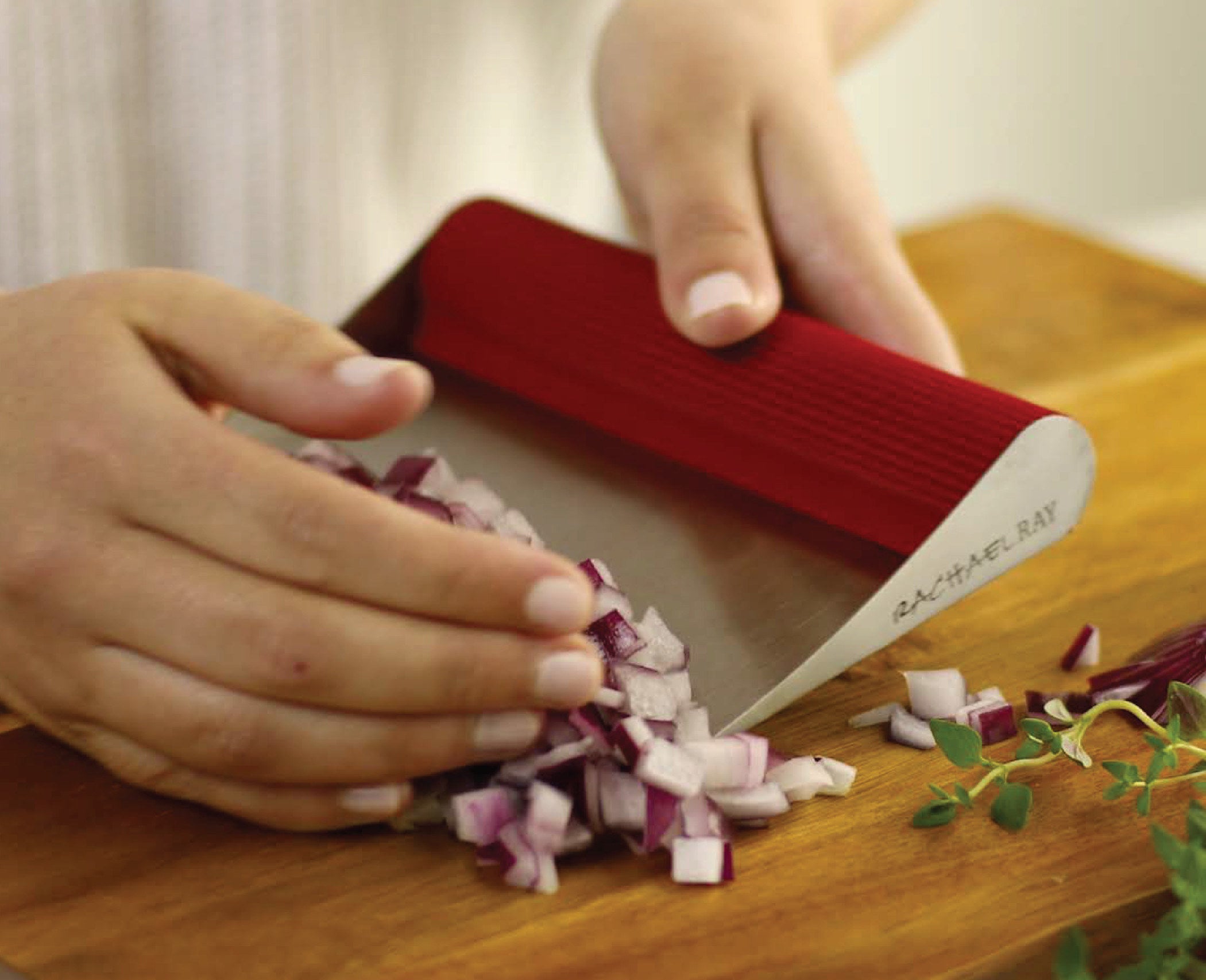 person using scraper to pick up chopped red onion