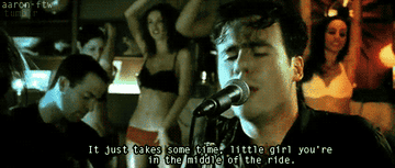 A GIF of Jim Adkins singing &quot;It just takes some time, little girl you&#x27;re in the middle of the ride&quot; from the music video for &quot;The Middle&quot;