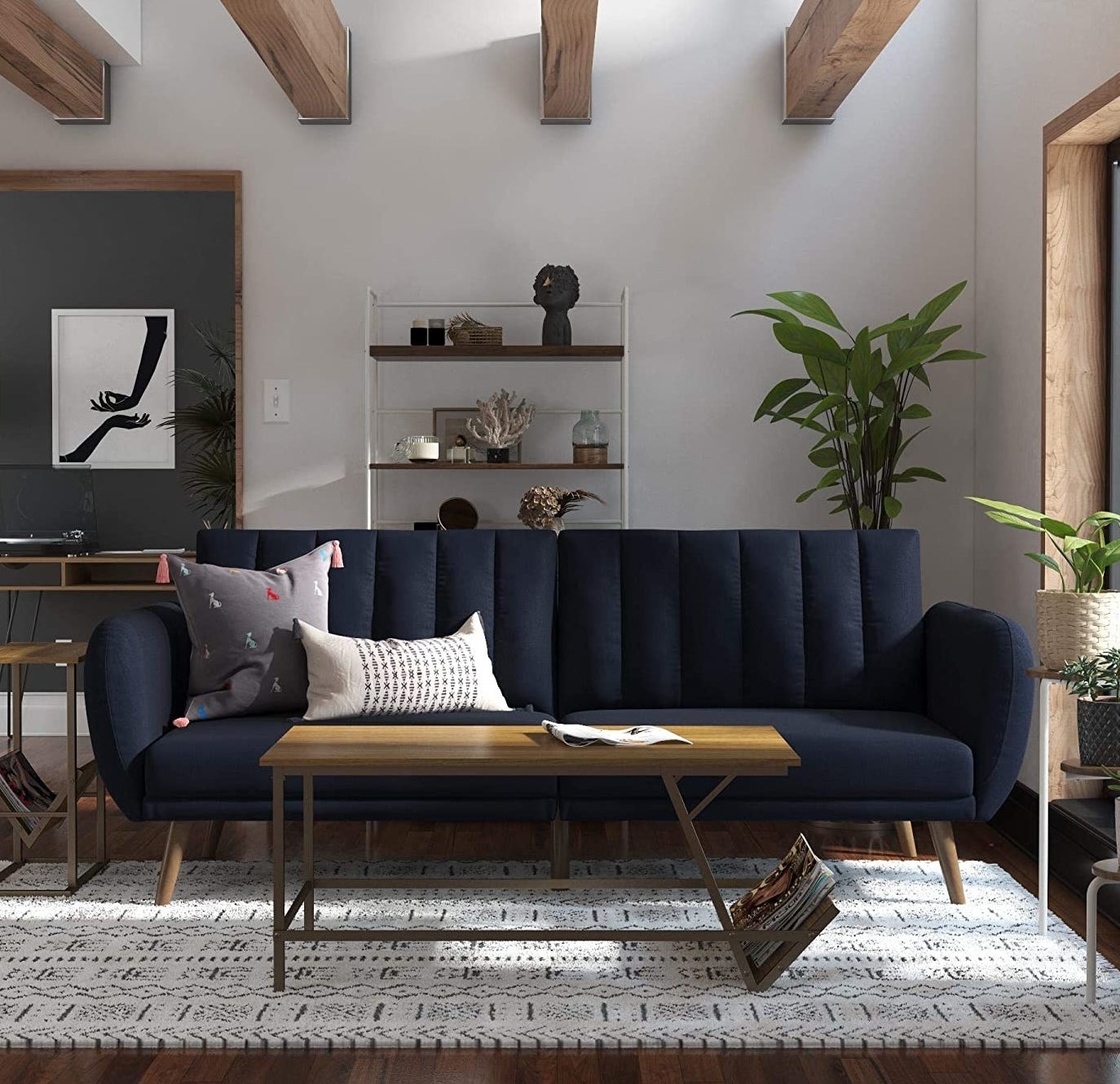 A navy blue futon with a tufted cushion back with slanted wooden legs in a living room.