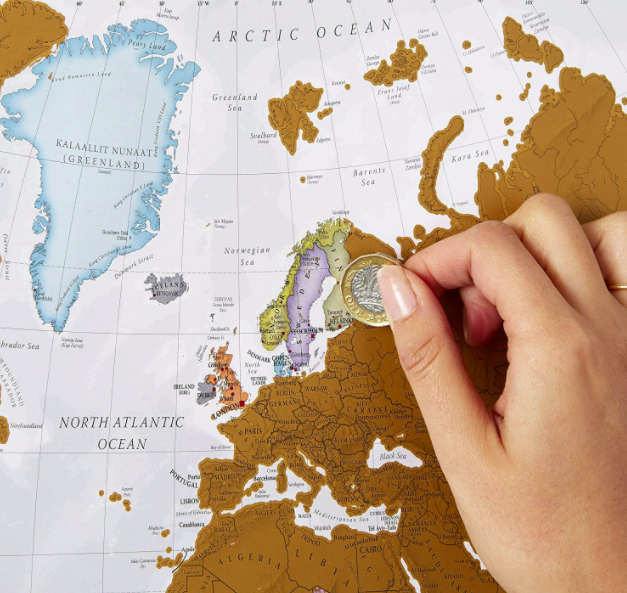 Hand uses coin to scratch off countries in Northern Europe on a scratch-off world map