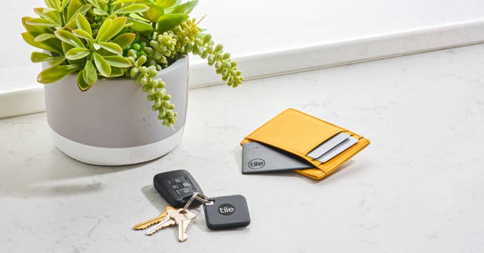 A square Tile tracker on a set of keys and a rectangular Tile tracker in a wallet