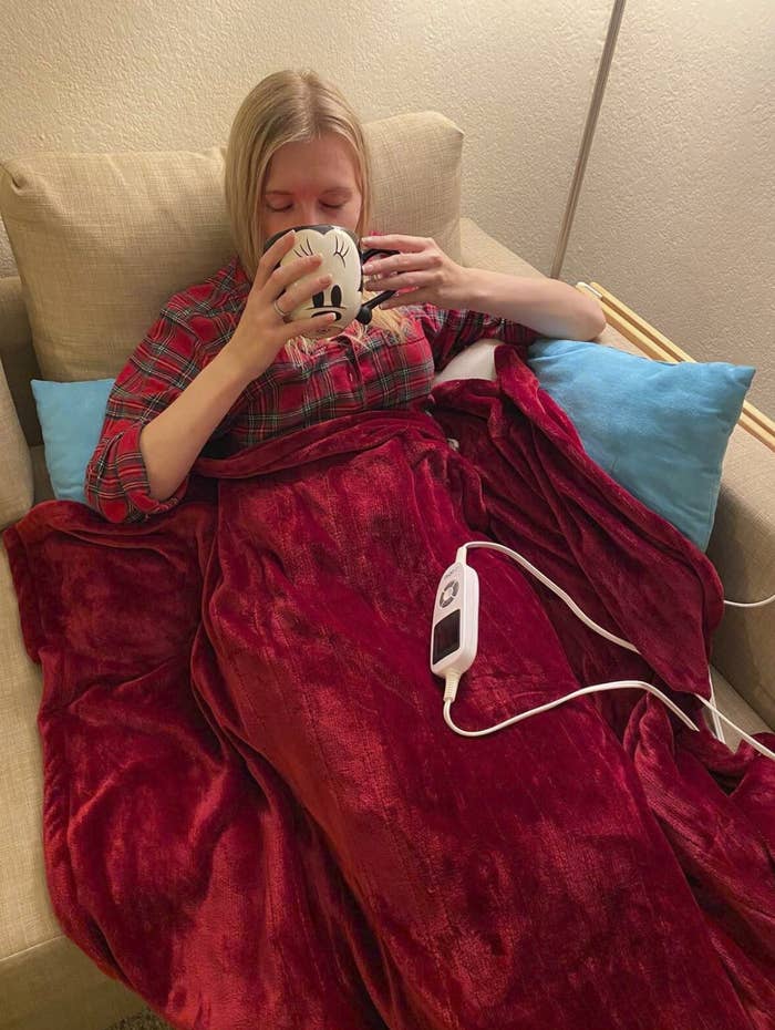 reviewer sitting under the blanket, drinking from a Mickey Mouse mug. Though it does appear she's in the "happiest place on earth," the mug's sold separately.