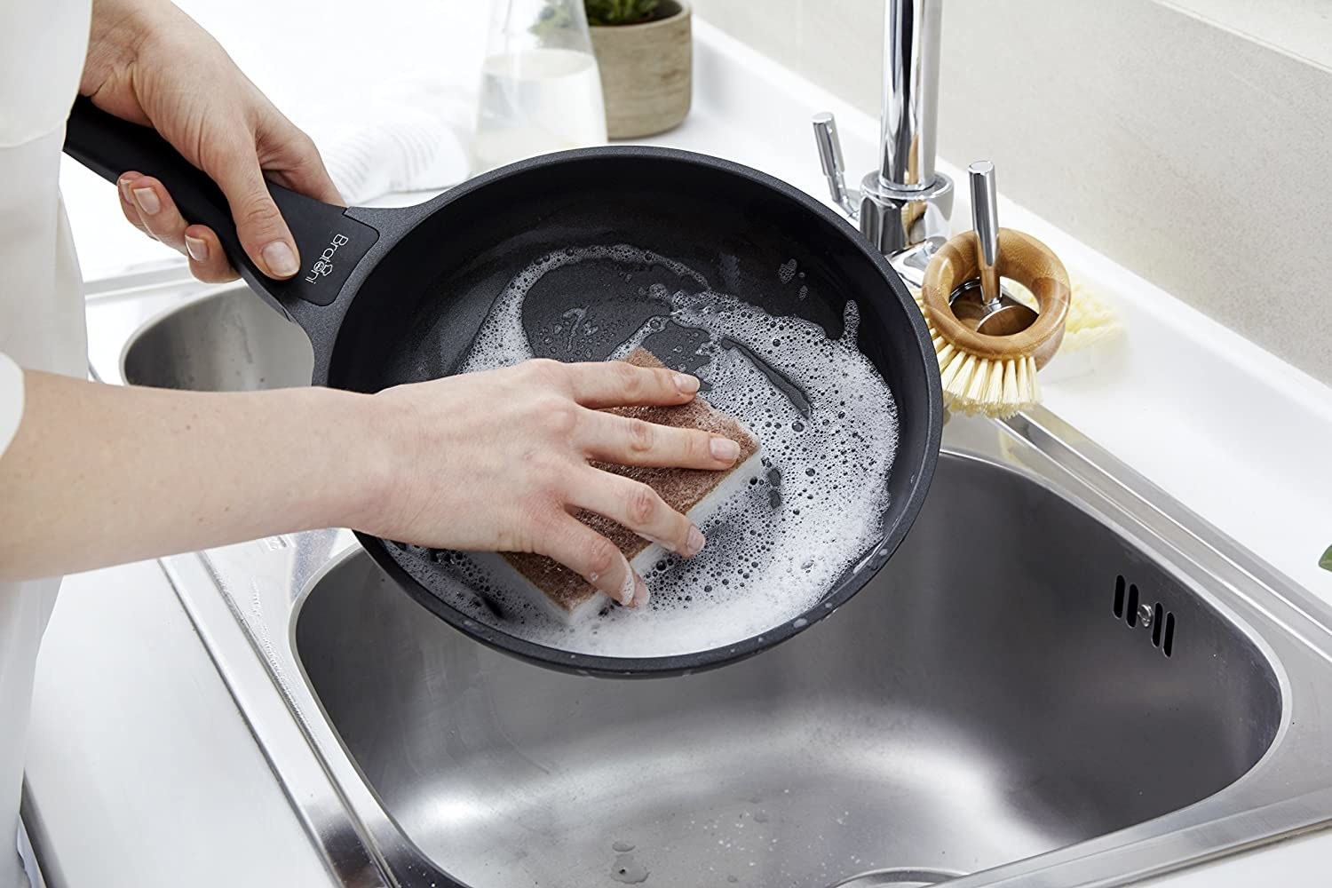 A person washes a cast iron pan with the scrubber