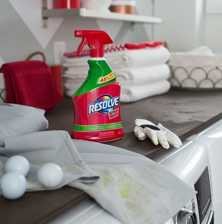 A bottle of the stain remover next to some grass-stained golf pants