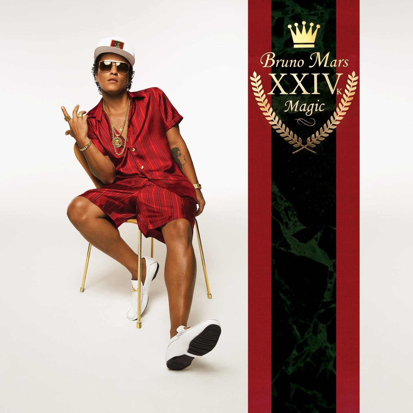 Bruno Mars sitting in a gold chair, wearing a red, silk co-ord, and lookin&#x27; fly. 