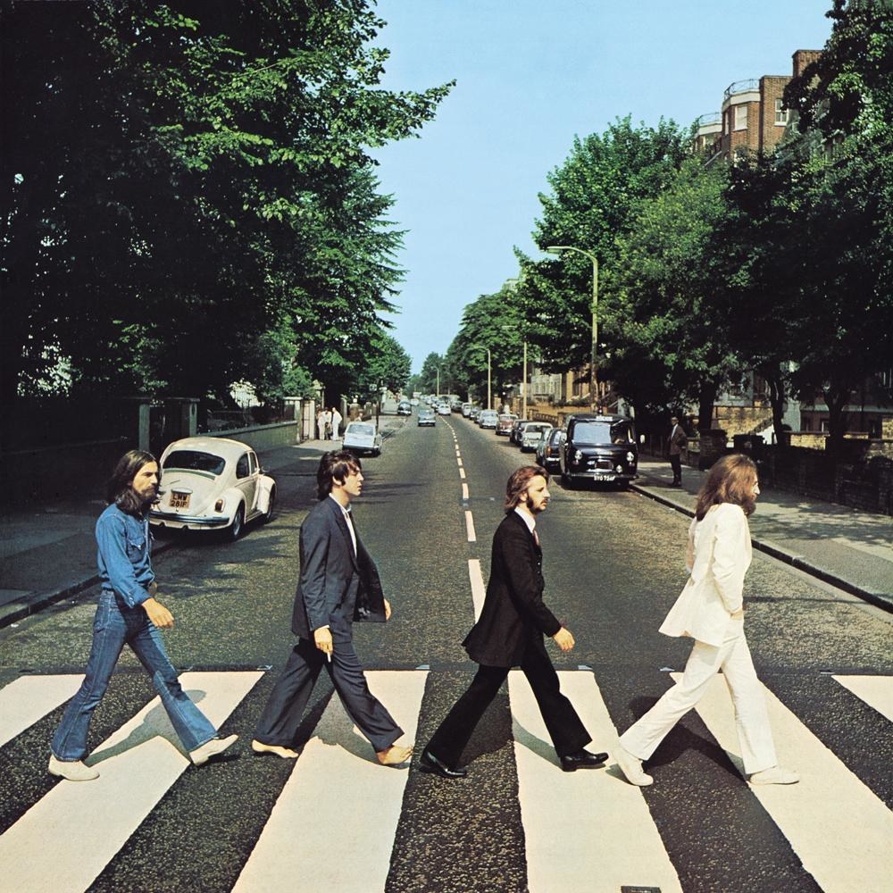 The Beatles walking across the crosswalk on Abbey Road in London. 