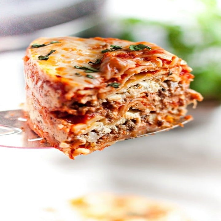 A slice of cheesy lasagna with ground beef on the inside.