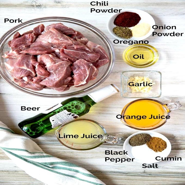 Ingredients for carnitas including pork, garlic, orange juice, lime juice, beer, and spices.