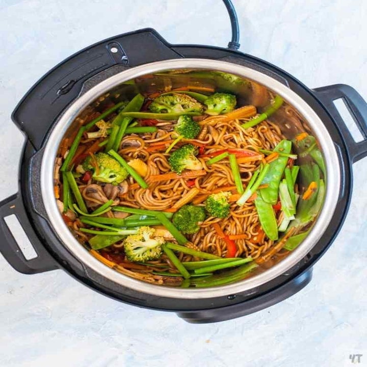 An Instant Pot filled with noodles, string beans, snap peas, broccoli, and carrots.