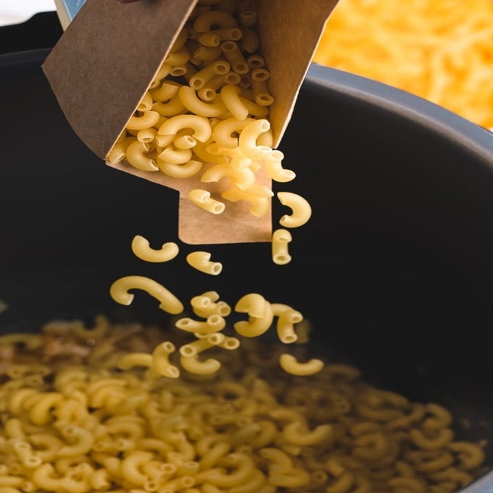 Pouring boxed elbow noodled into an Instant Pot.