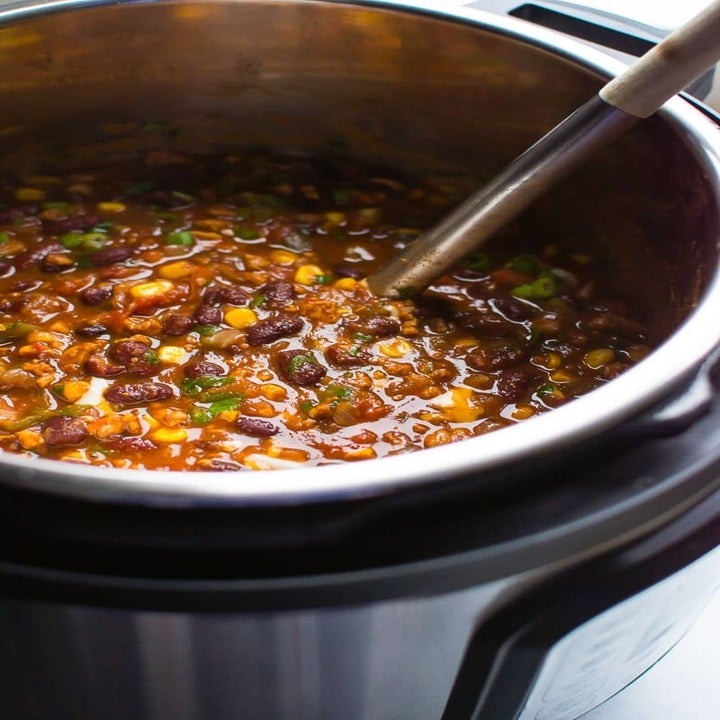 A ladle scooping turkey and bean chili from an Instant Pot.