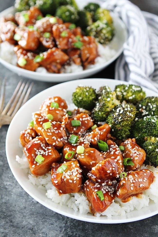 A bowl of sticky, glazed sesame chicken with broccoli over rice.