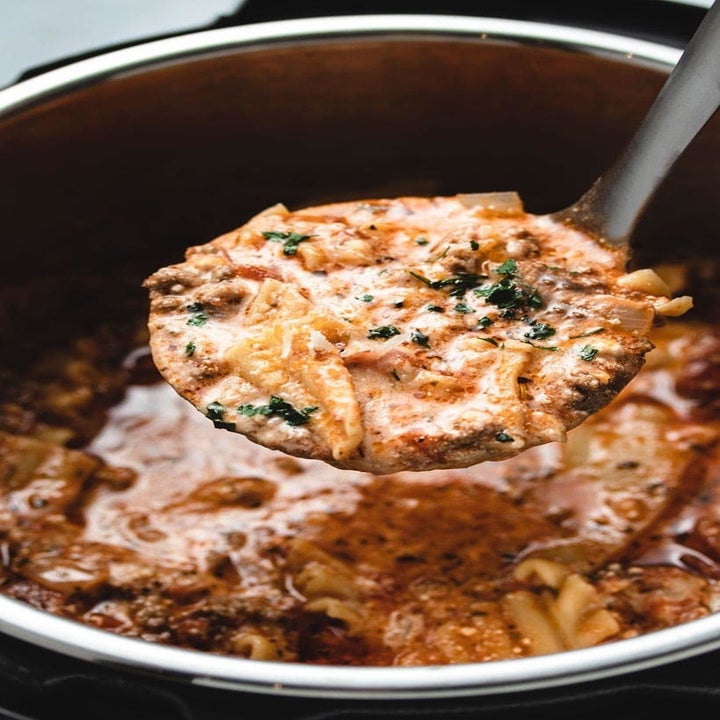 A ladle taking a spoonful of creamy, cheesy lasagna soup.