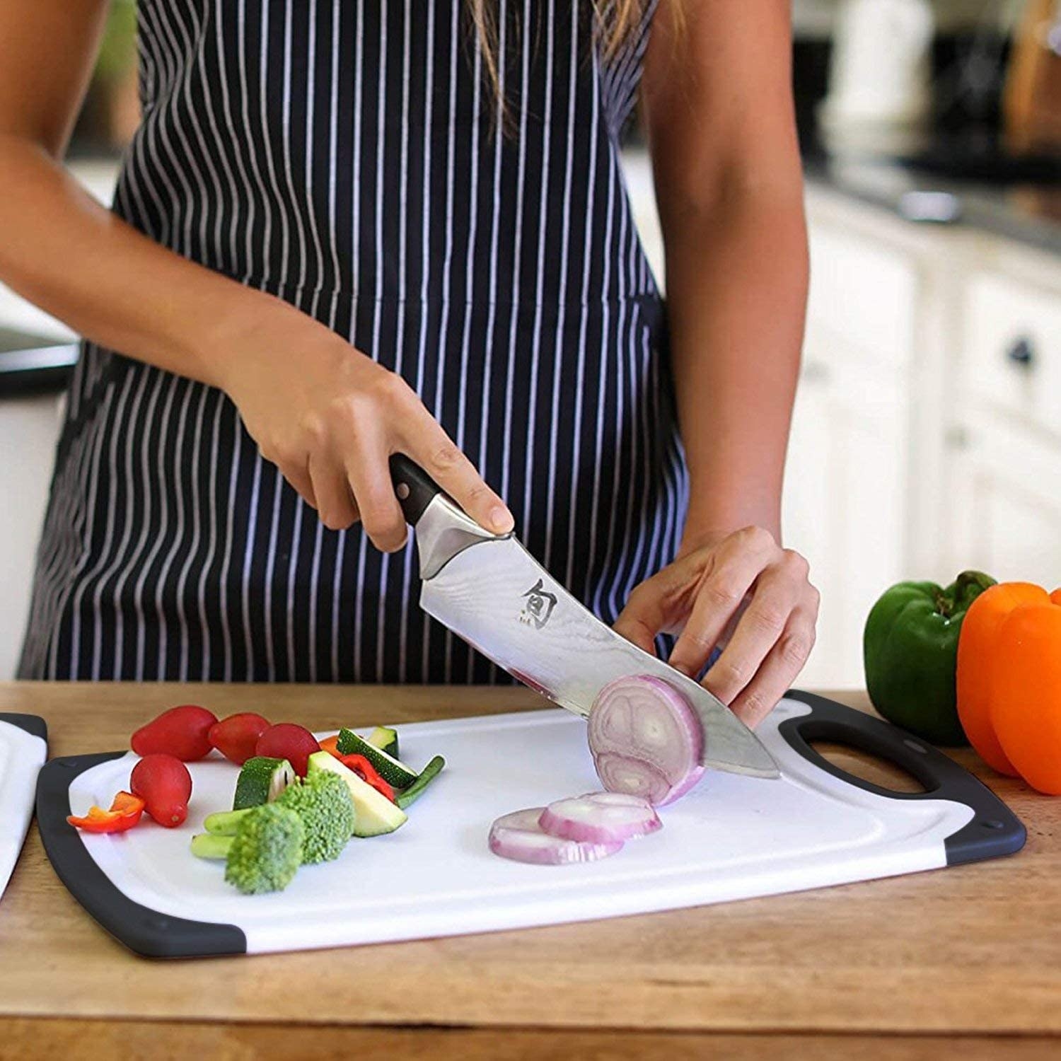A person cutting vegetables on the largest cutting board