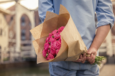 A man holding a bouquet of flowers behind his back.