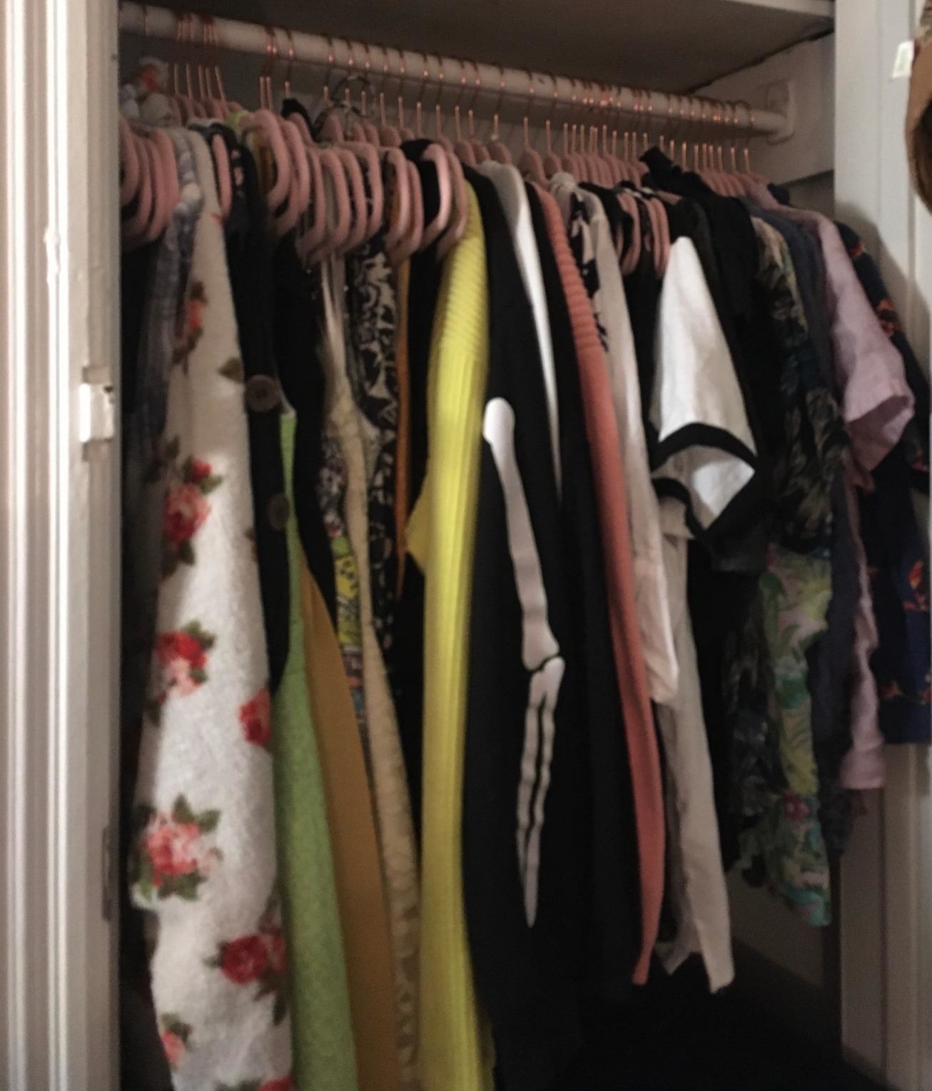 A customer&#x27;s closet filled with clothes hanging from light pink SONGMICS Velvet Hangers