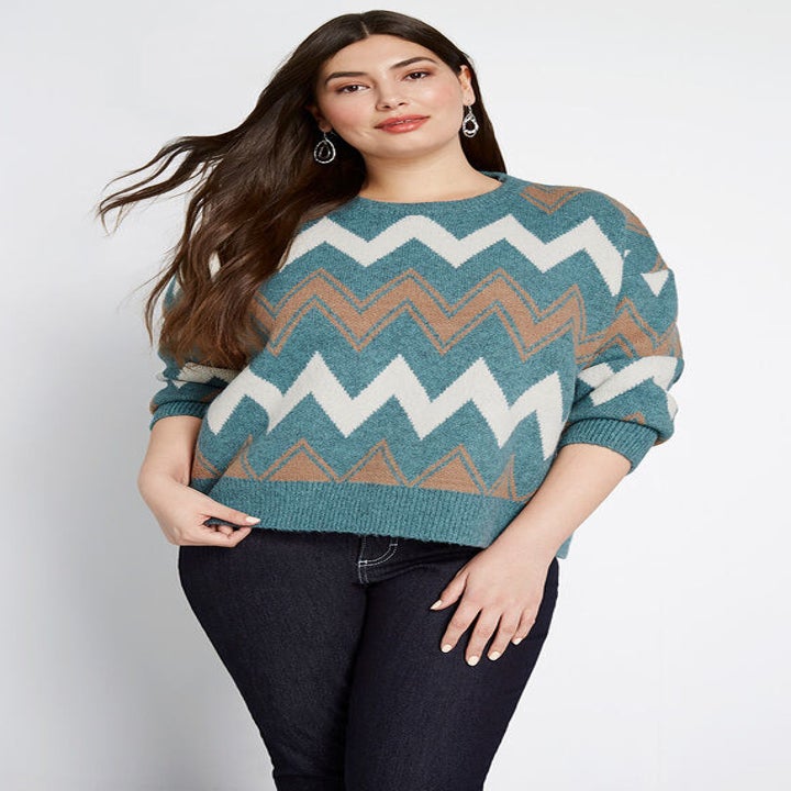 A model in the teal, tan, and white zig zag pattern pullover sweater