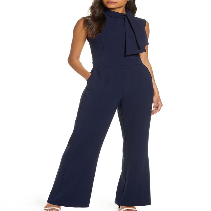 Model in the sleeveless, tie-neck, navy jumpsuit