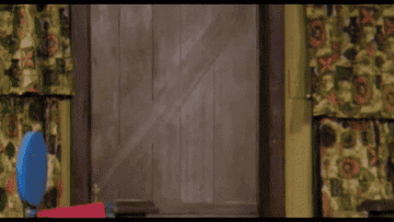 GIF of Fred Rogers walking through a door and smiling