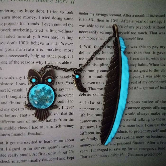 An owl and feather shaped glow-in-the-dark bookmark kept on a text-filled page.