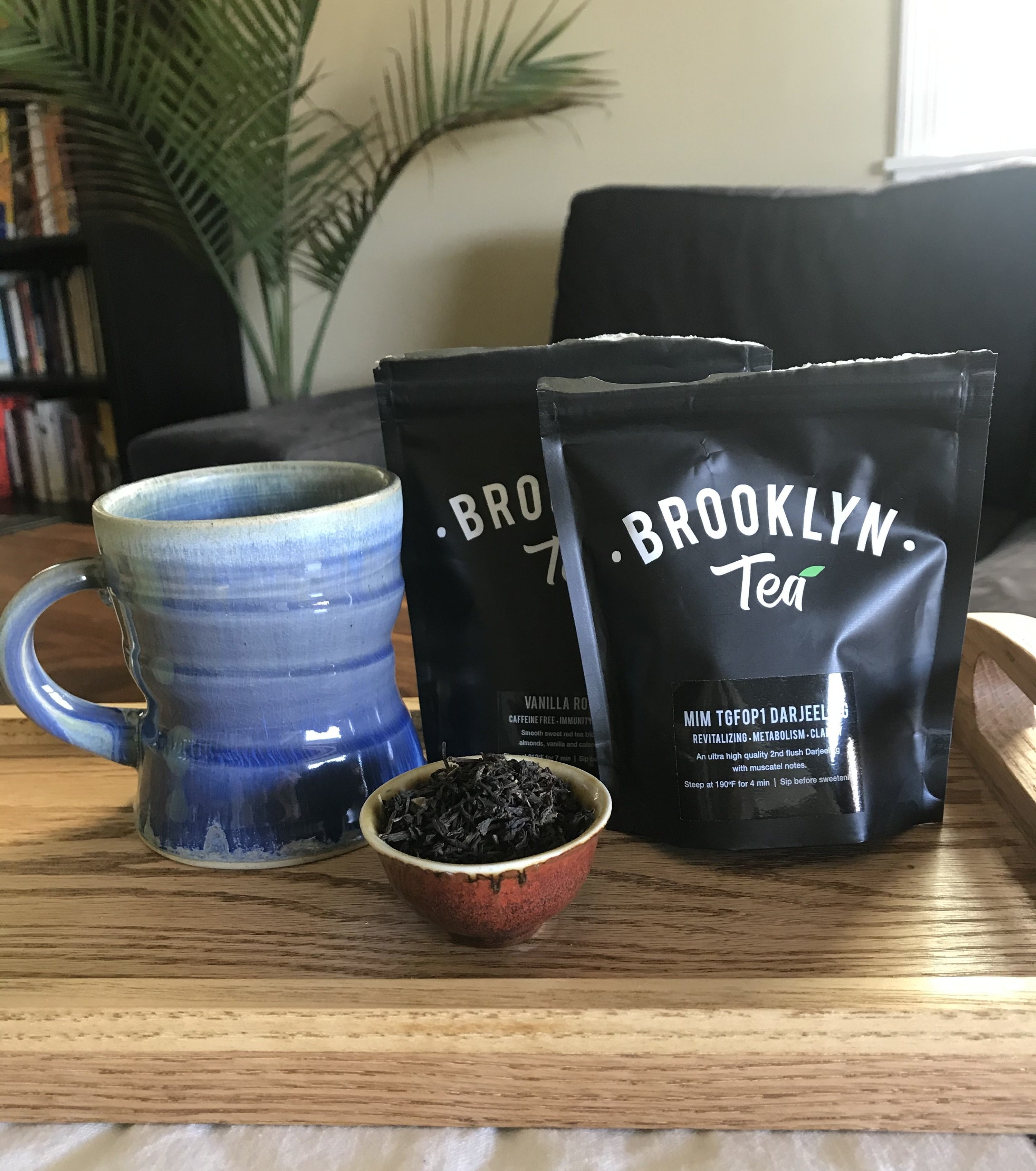 the writer's two bags of loose leaf tea on a wooden tray with a mug and small saucer of looseleaf darjeeling