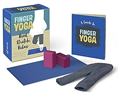 A finger yoga book with a small pair of pants a mat and two yoga blocks