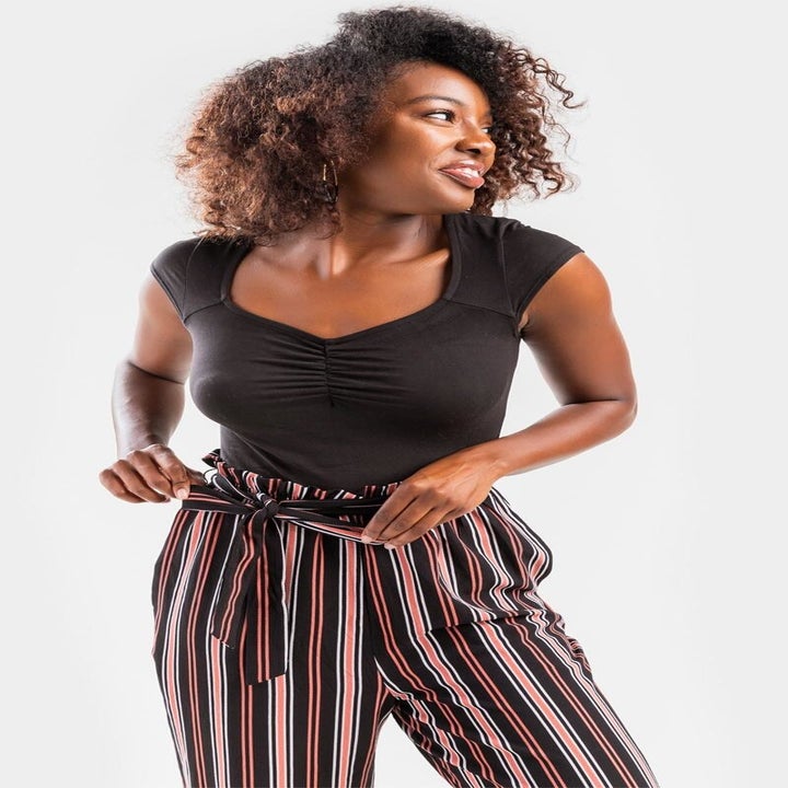 A model in the jumpsuit with a black cap sleeve bodice and striped pants