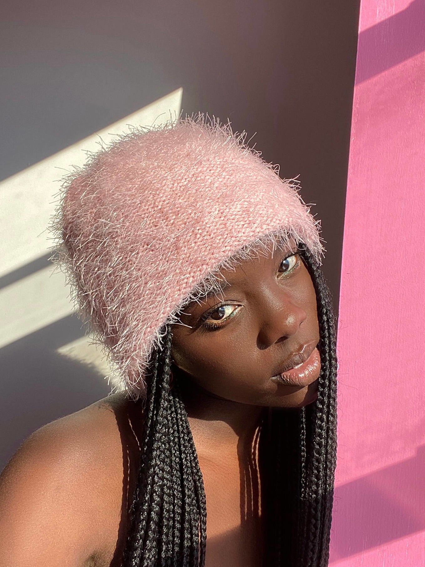 A model wears a fuzzy, light pink, knit beanie