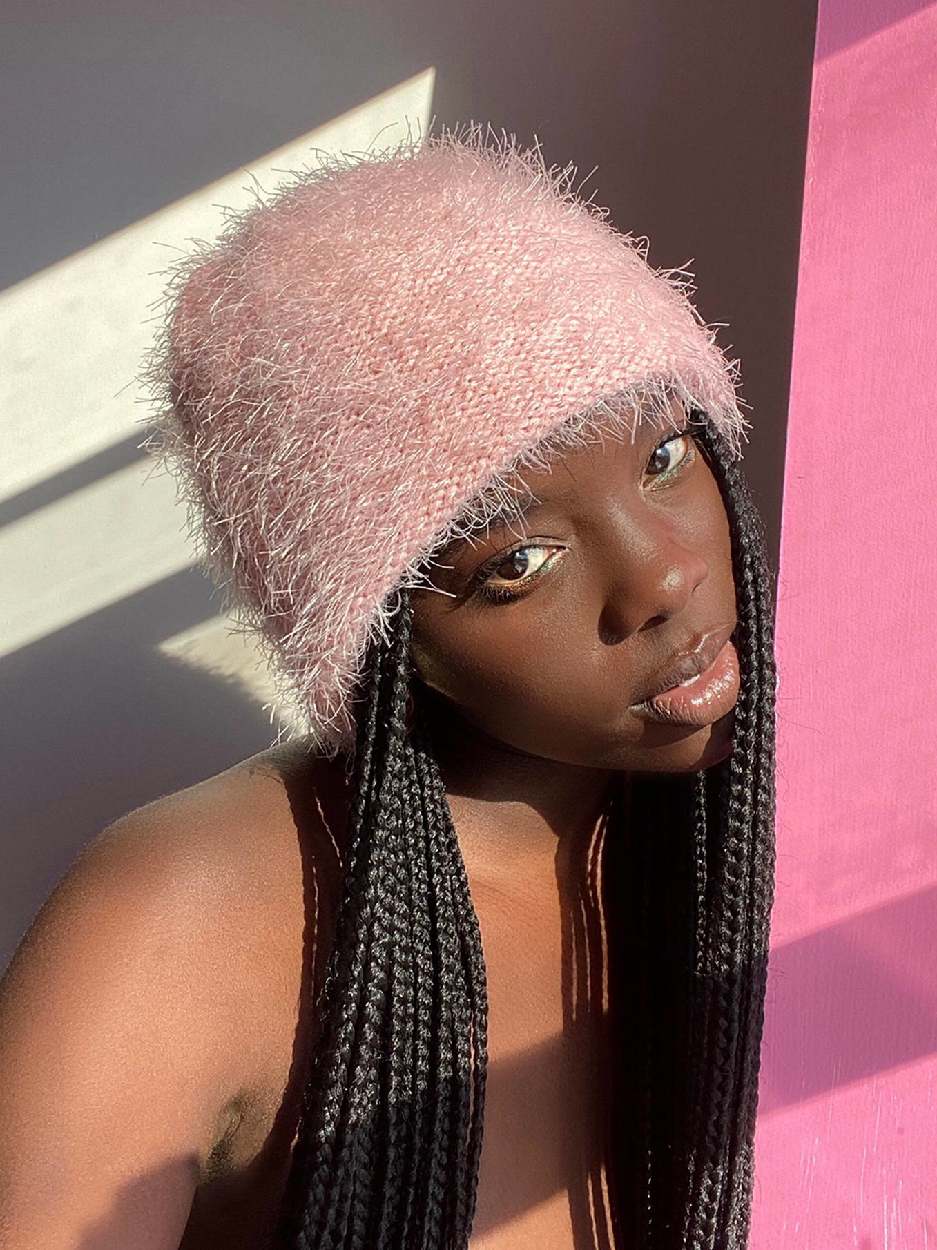 A model wears a fuzzy, light pink, knit beanie