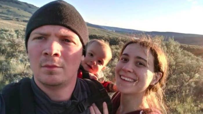 A family with their young son stand in the wilderness, smiling at the camera