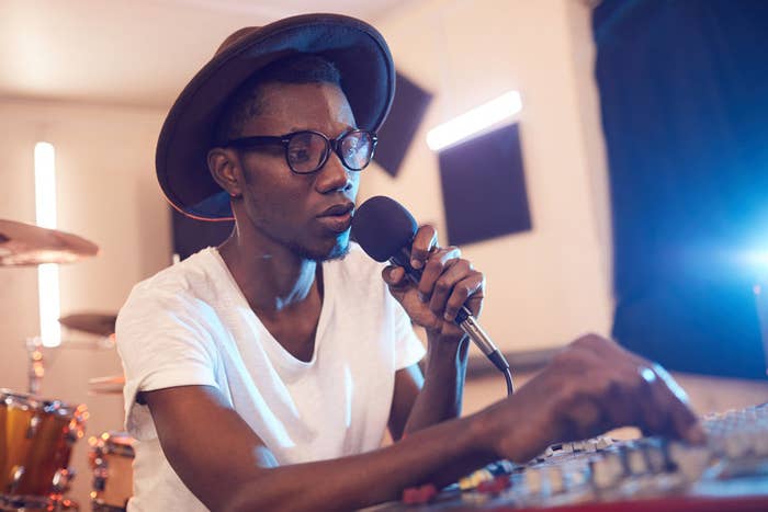 A man sits in a studio holding a mic as he writes a song