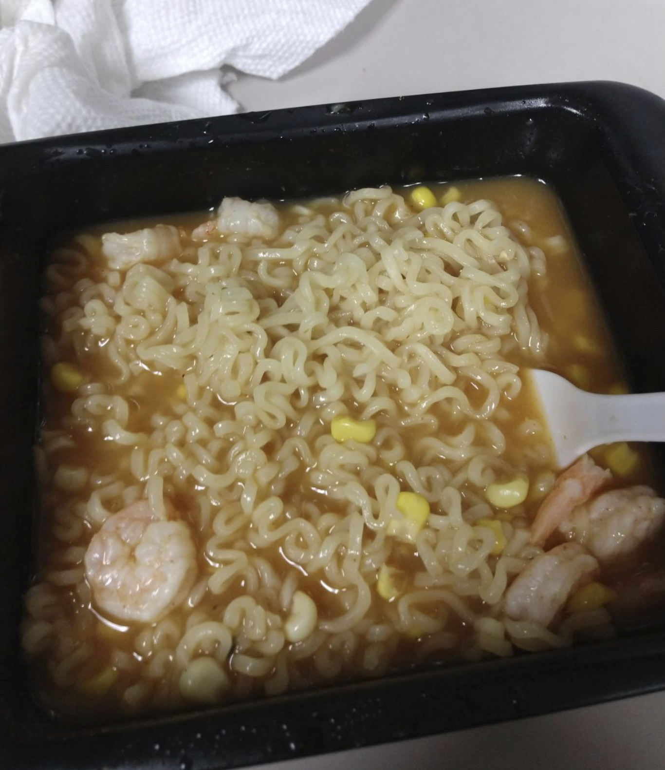 bowl of cooked noodles with broth, shrimp, and corn