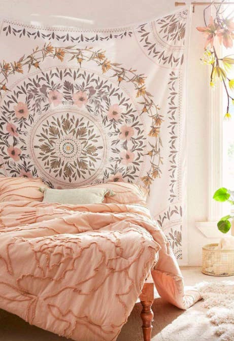 Pink and white floral medallion tapestry hanging above a bed with a pink comforter