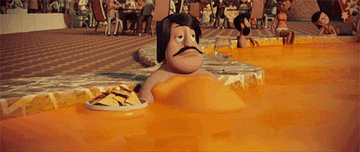 Man from &quot;Cloudy with a chance of meatballs&quot; in a pool of nacho cheese, licking nachos off his arm.