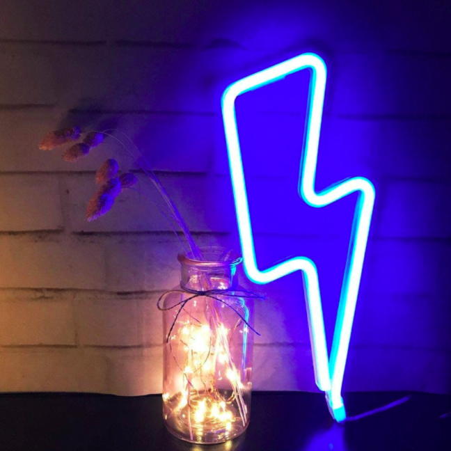 Neon blue lightning bolt wall light on a table next to a brick wall