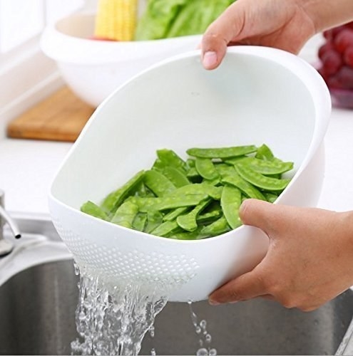 A person draining water from the colander filled with pea pods.