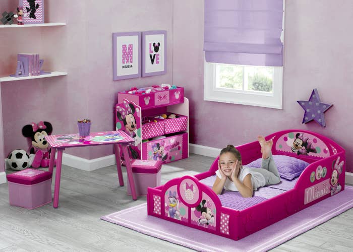 child sitting on a pink bed in a minnie mouse-themed bedroom