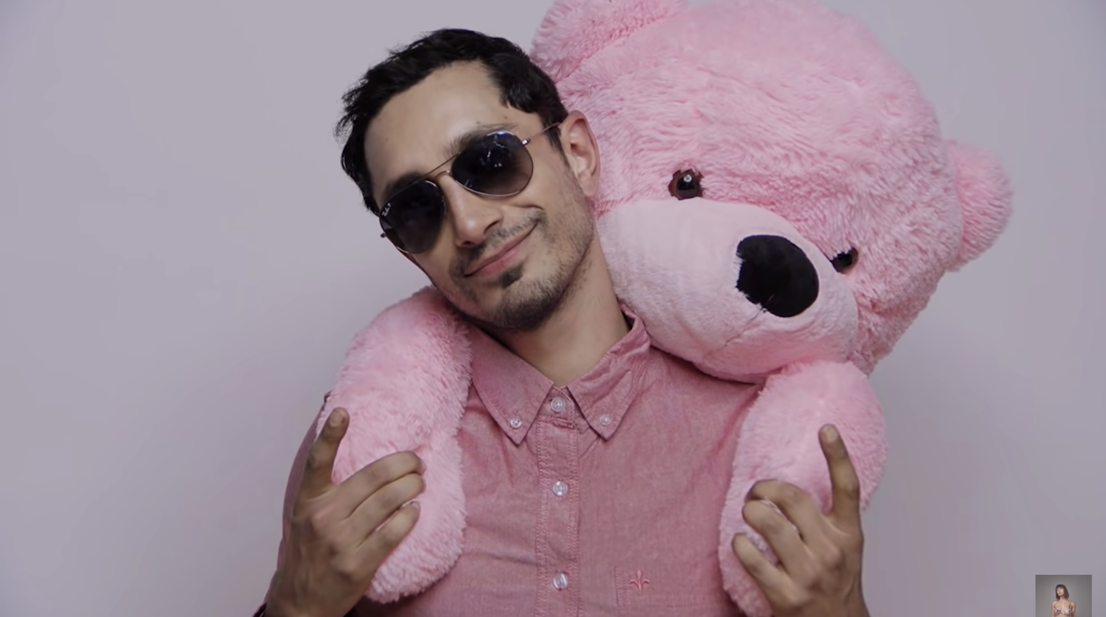 Riz holding a pink teddy bear on his back piggy-back style. 